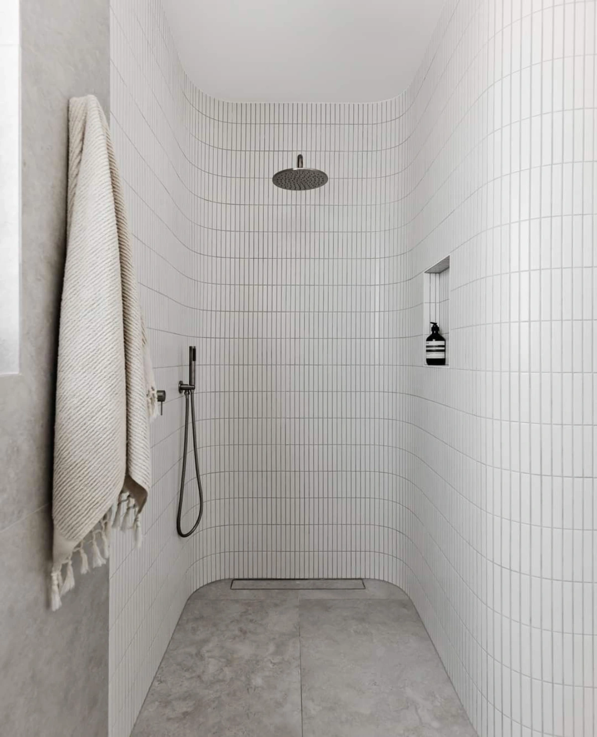 Modern wet room bathroom featuring curved walls and channel drain