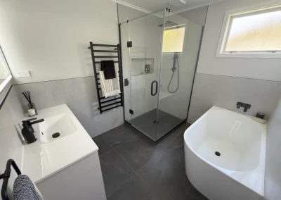 Spode bathroom renovation with a freestanding bath, glass shower, vanity and charcoal floor tiles